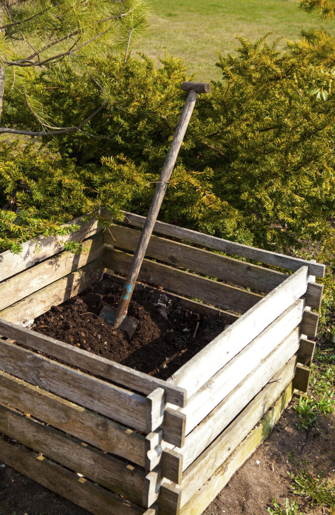 Backyard compost bin with homemade compost and a shovel in it